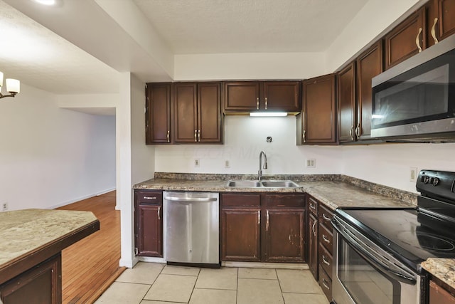 kitchen featuring light tile patterned floors, stainless steel appliances, dark brown cabinets, and sink