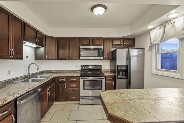 kitchen featuring sink, light tile patterned flooring, dark brown cabinets, and appliances with stainless steel finishes
