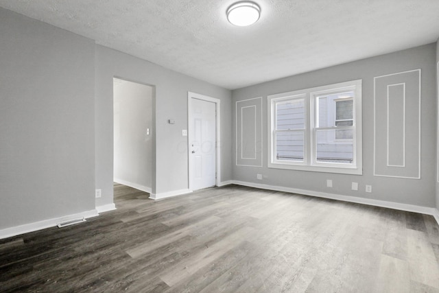 spare room featuring a textured ceiling and dark hardwood / wood-style flooring