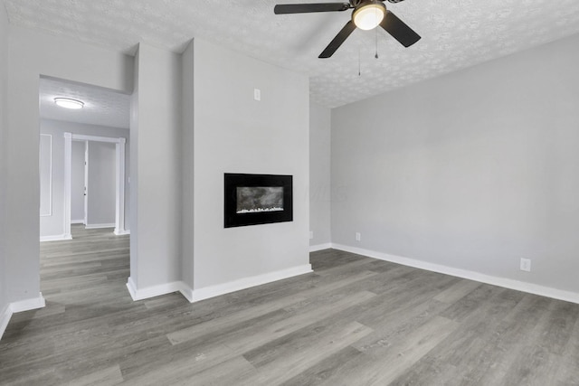 unfurnished living room featuring a fireplace, wood-type flooring, a textured ceiling, and ceiling fan