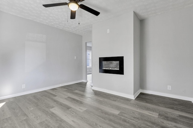 unfurnished living room featuring hardwood / wood-style floors, ceiling fan, and a textured ceiling