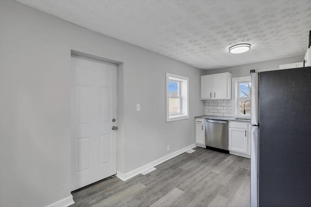 kitchen featuring white cabinetry, sink, stainless steel appliances, backsplash, and a textured ceiling