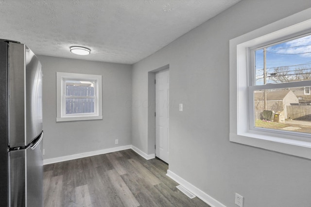 unfurnished dining area featuring plenty of natural light, dark wood-type flooring, and a textured ceiling