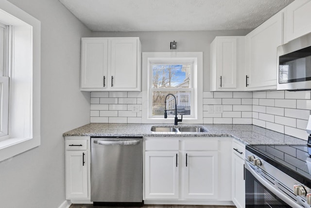 kitchen featuring light stone countertops, white cabinetry, sink, and stainless steel appliances