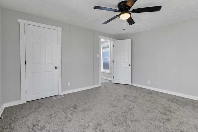 carpeted empty room featuring ceiling fan and a textured ceiling