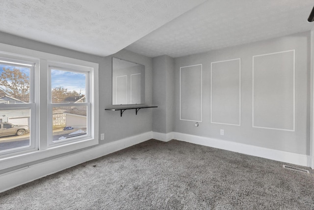 carpeted empty room featuring a textured ceiling