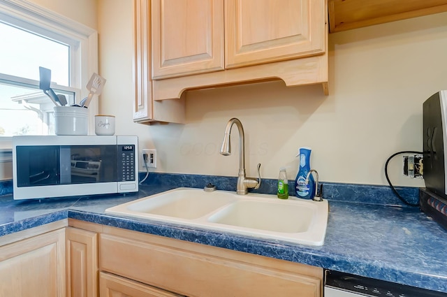 kitchen featuring light brown cabinetry, dishwasher, and sink