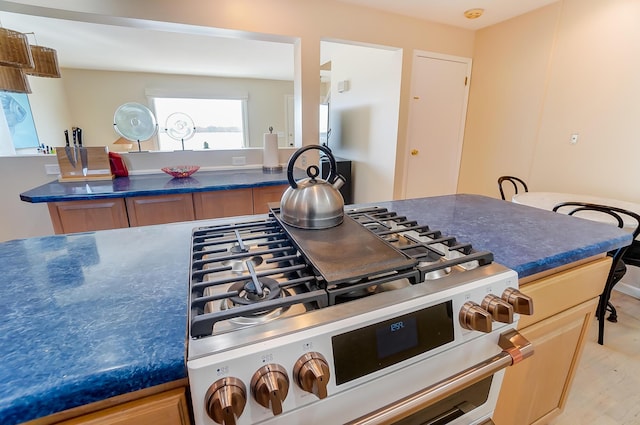 kitchen featuring high end range, light brown cabinetry, and light hardwood / wood-style flooring