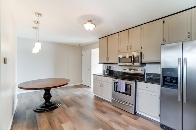 kitchen with pendant lighting, dark stone counters, white cabinets, light hardwood / wood-style floors, and stainless steel appliances