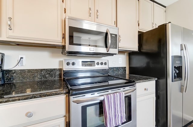 kitchen with white cabinetry, stainless steel appliances, and dark stone counters