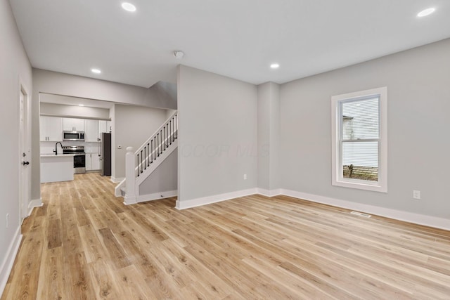 spare room with light hardwood / wood-style floors and sink