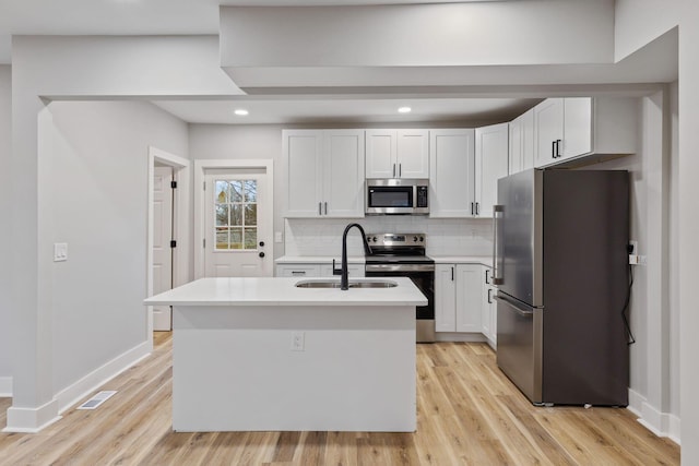 kitchen featuring white cabinets, appliances with stainless steel finishes, and a center island with sink