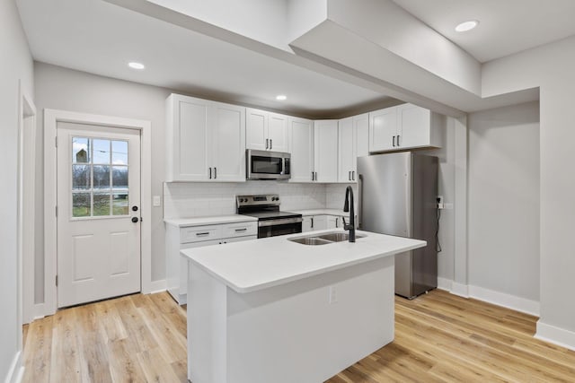 kitchen featuring white cabinetry, sink, stainless steel appliances, backsplash, and light hardwood / wood-style floors