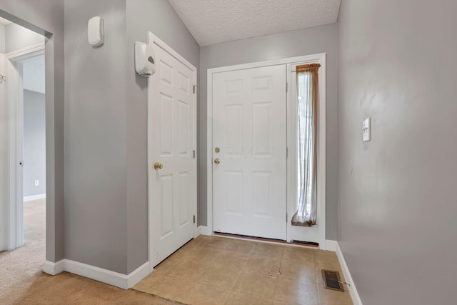 foyer entrance featuring light colored carpet and a textured ceiling