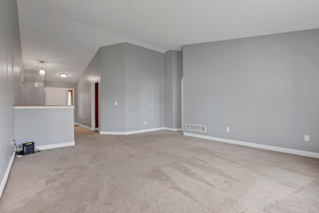 carpeted empty room with high vaulted ceiling