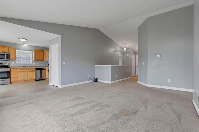 unfurnished living room with a textured ceiling, light colored carpet, lofted ceiling, and sink