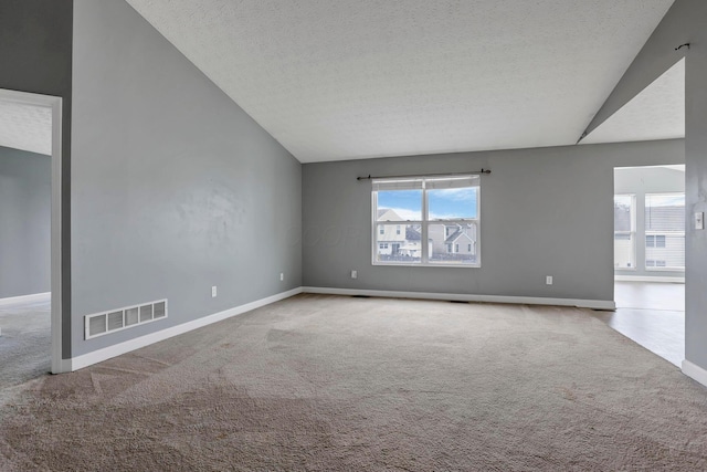 carpeted spare room featuring a textured ceiling and vaulted ceiling