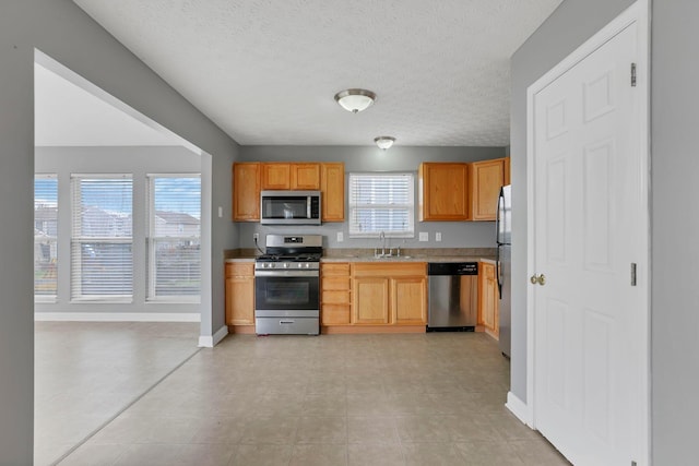 kitchen featuring a textured ceiling, stainless steel appliances, and sink