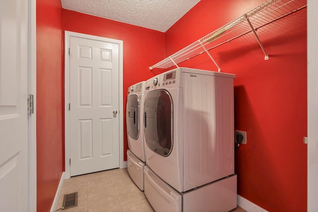 clothes washing area featuring a textured ceiling and washing machine and dryer