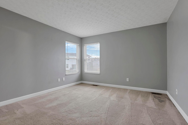 carpeted empty room with a textured ceiling