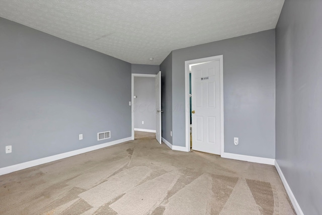 carpeted empty room with a textured ceiling