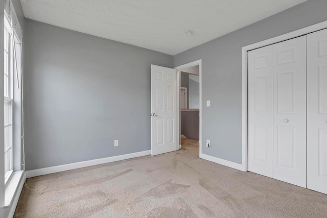 unfurnished bedroom with multiple windows, light carpet, and a closet