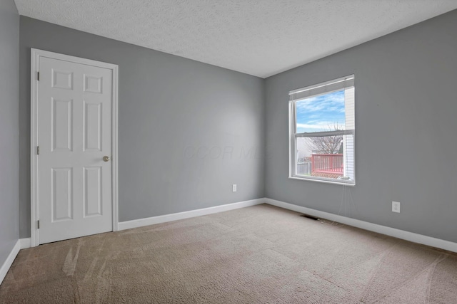 carpeted empty room featuring a textured ceiling