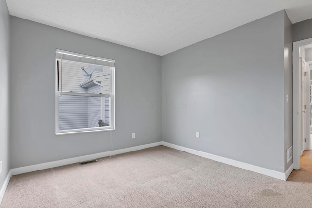 empty room with light colored carpet and a textured ceiling