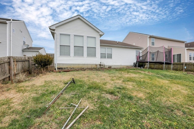 back of house with a trampoline and a yard