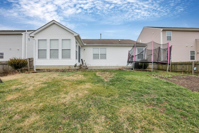 back of property featuring a yard and a trampoline