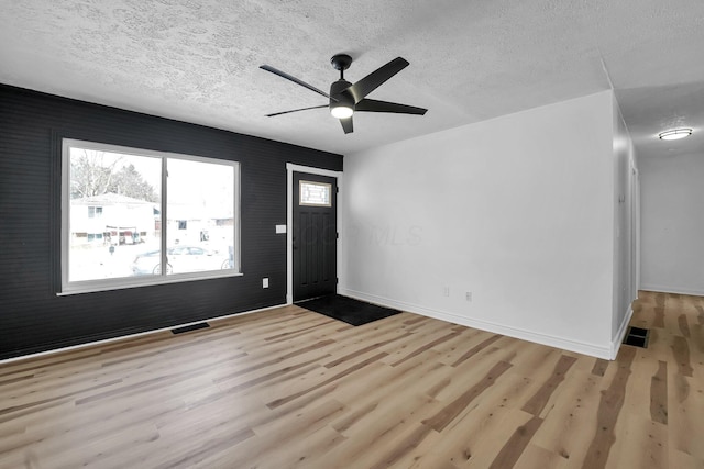 entrance foyer featuring a textured ceiling, visible vents, and light wood-style floors