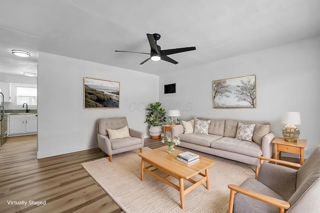 living room featuring ceiling fan, wood finished floors, and baseboards