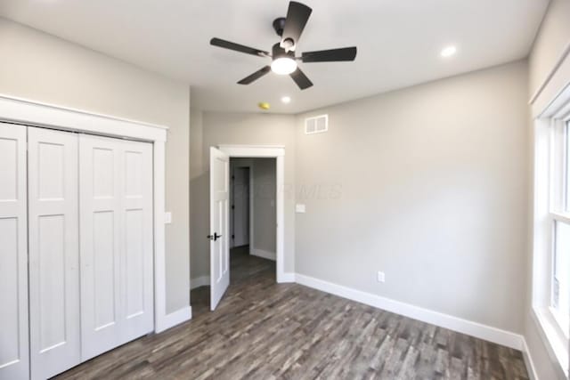 unfurnished bedroom featuring multiple windows, a closet, wood-type flooring, and ceiling fan