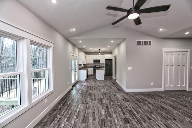 unfurnished living room featuring vaulted ceiling, dark hardwood / wood-style floors, and ceiling fan