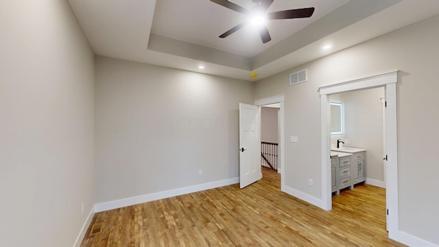 unfurnished bedroom featuring light hardwood / wood-style floors and a tray ceiling