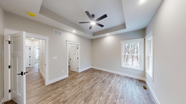 unfurnished bedroom featuring light hardwood / wood-style floors and a raised ceiling