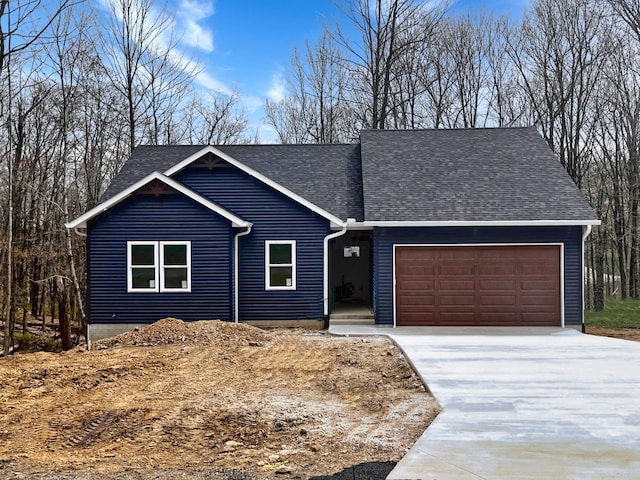 view of front of property with concrete driveway, a shingled roof, and an attached garage