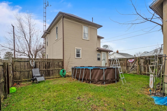 rear view of house featuring a fenced in pool and a lawn