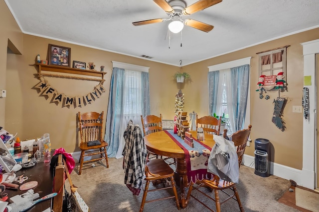 carpeted dining room with a textured ceiling, ceiling fan, and ornamental molding