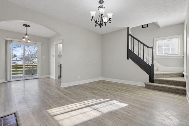 interior space featuring plenty of natural light, light hardwood / wood-style floors, a textured ceiling, and an inviting chandelier