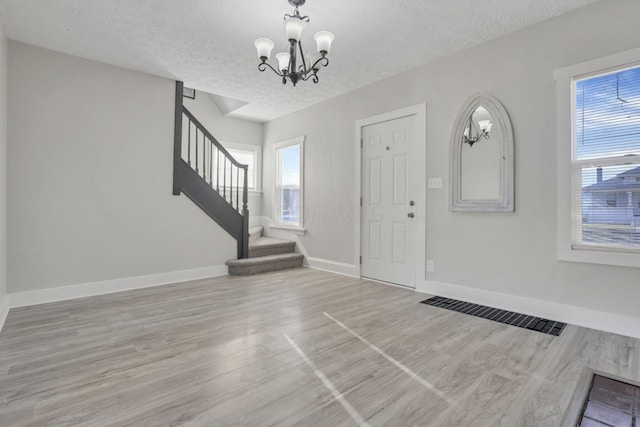 foyer featuring hardwood / wood-style floors, a textured ceiling, an inviting chandelier, and plenty of natural light