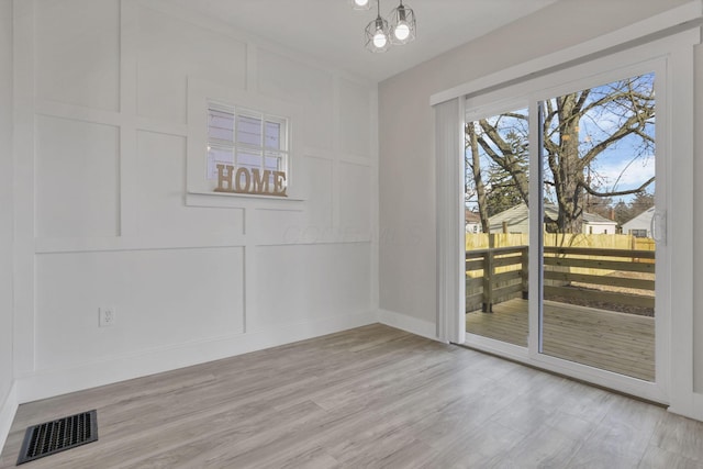 unfurnished dining area with a chandelier and light hardwood / wood-style floors