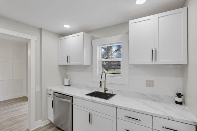 kitchen with light stone countertops, white cabinetry, stainless steel dishwasher, and sink