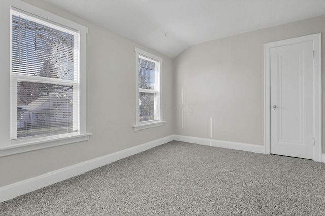 carpeted empty room with lofted ceiling