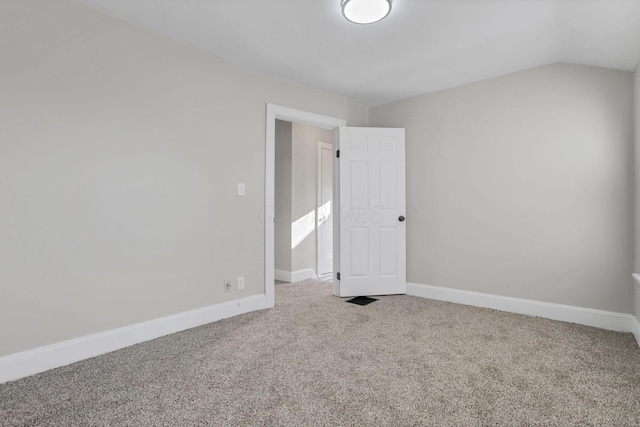 carpeted empty room featuring vaulted ceiling