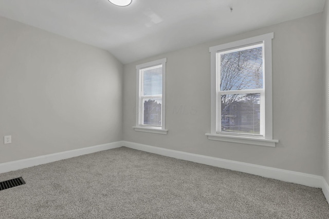 carpeted spare room with vaulted ceiling