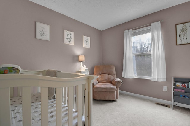 carpeted bedroom with a textured ceiling and a nursery area