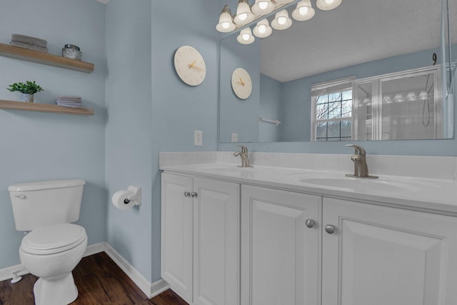 bathroom featuring hardwood / wood-style flooring, vanity, an enclosed shower, and toilet