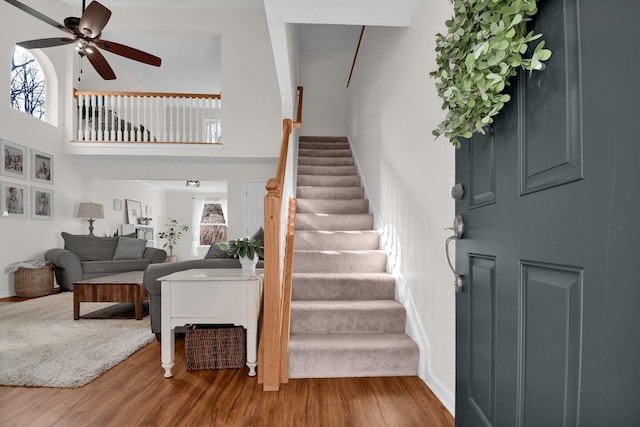 entryway featuring ceiling fan, a towering ceiling, and wood-type flooring