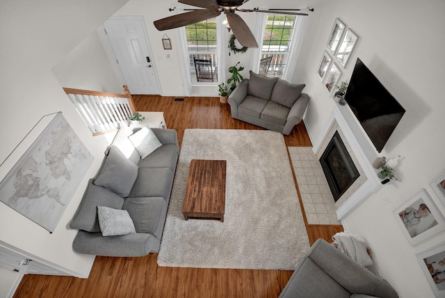 living room with ceiling fan, light wood-type flooring, and a tile fireplace